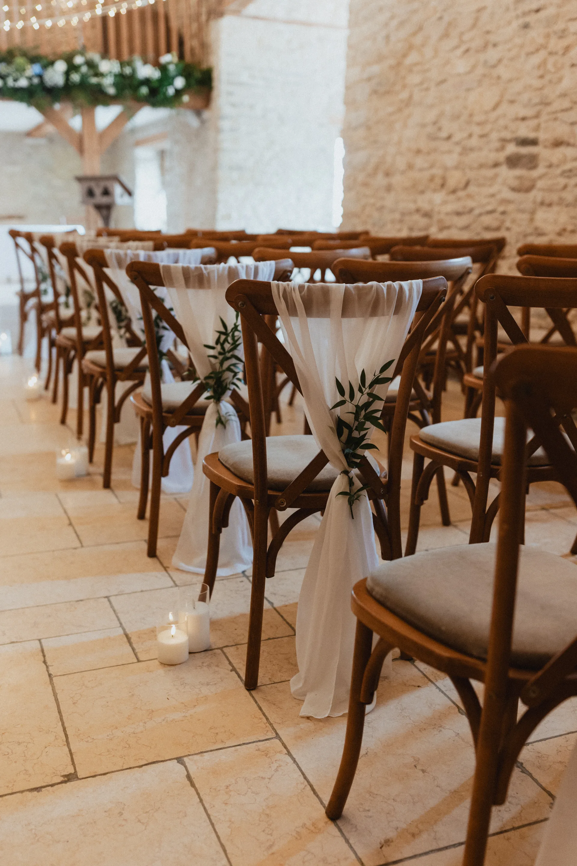 Ceremony setup with wooden chairs and floral aisle at Kingscote Barn