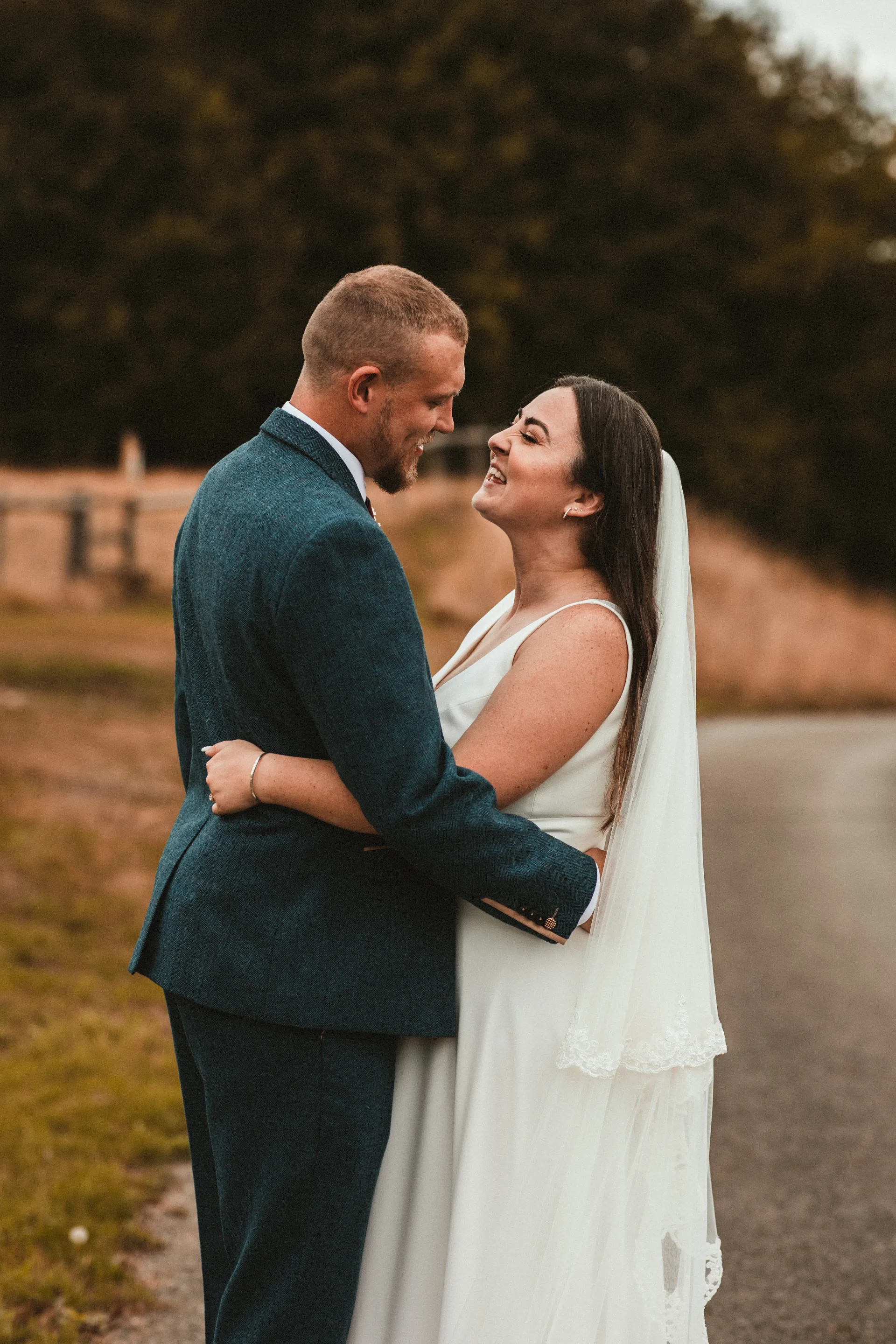Bride and groom walking through fields at golden hour near Kingscote Barn