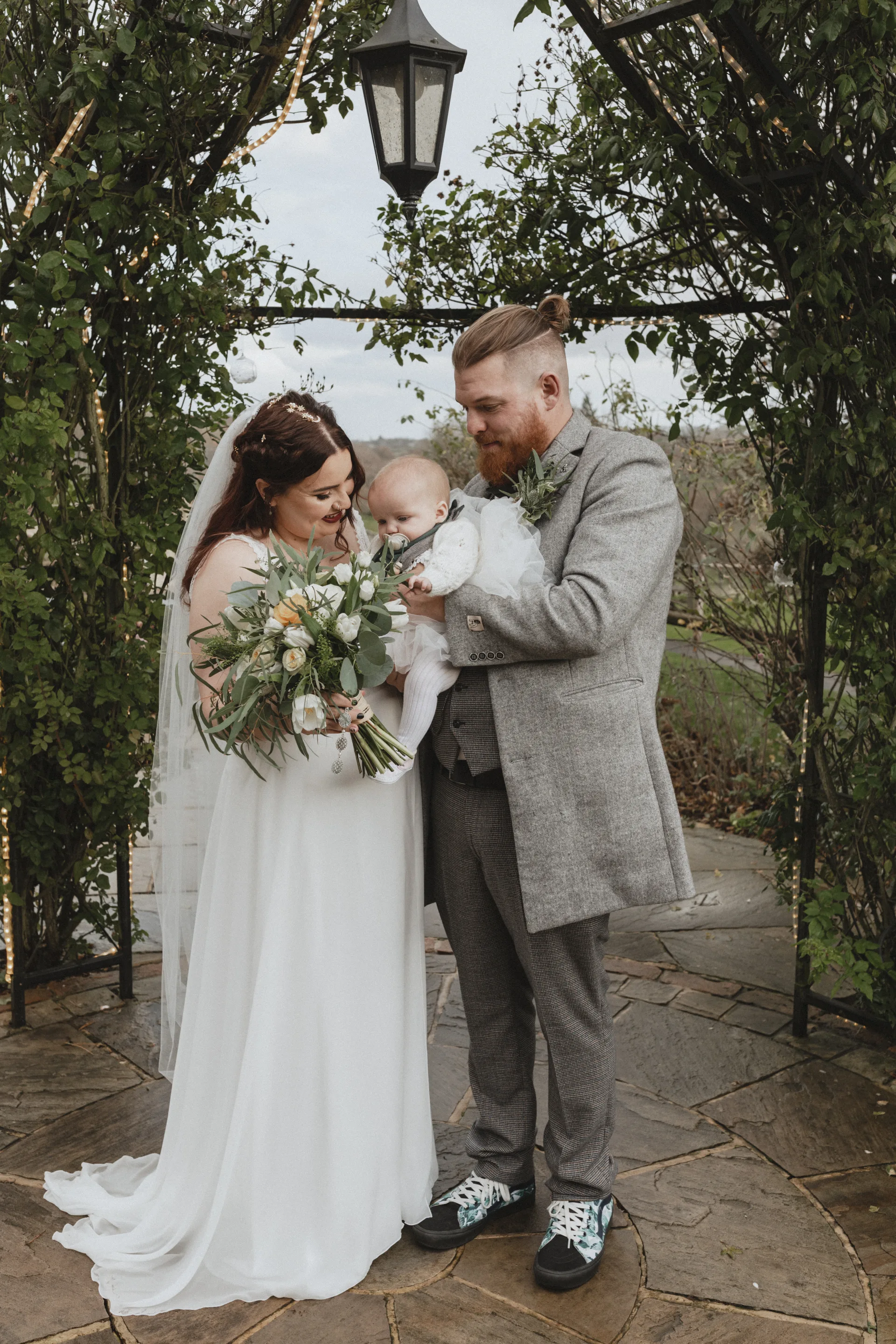 Bride and groom holding their baby during their wedding at Kingscote Barn